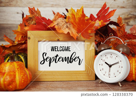 Welcome September text with alarm clock and maple leaf decoration on wooden background Welcome September text with alarm clock and maple leaf decoration on wooden background 128338370