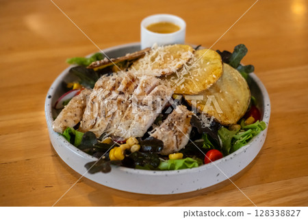 Grilled chicken salad with sauce, on plate for served in a restaurant Grilled chicken salad with sauce, on plate for served in a restaurant 128338827