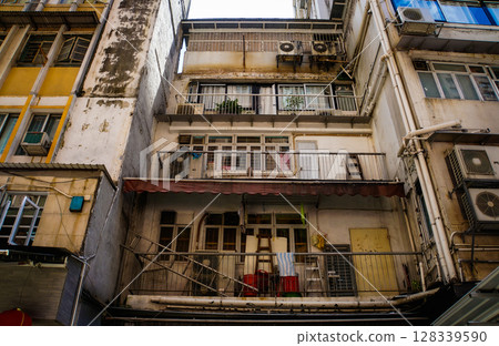 Close-up of yellow building facade with windows, pipes in Hong Kong 128339590