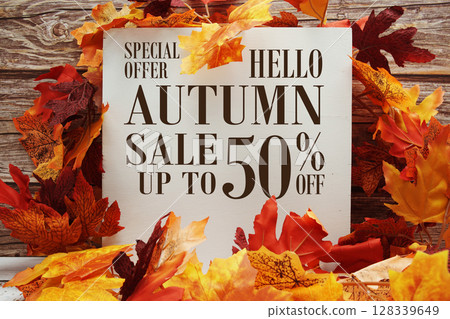 Autumn Sale 50% off text with maple leaf decoration on wooden background 128339649