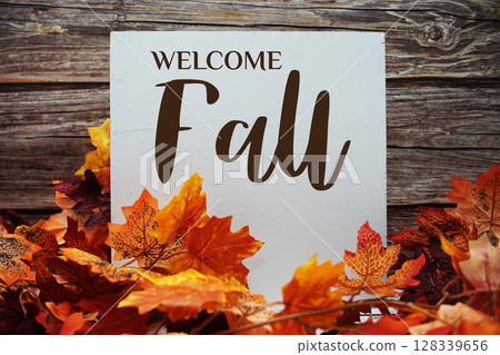 Welcome Fall text with maple leaf decoration on wooden background 128339656