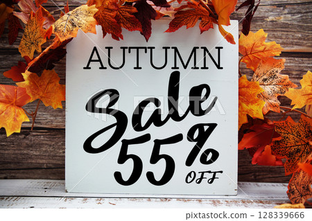Autumn Sale 55% off text with maple leaf decoration on wooden background 128339666