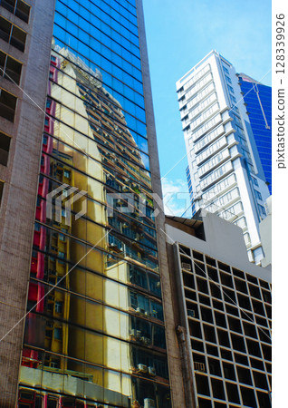 A modern skyscraper reflects the blue sky with its glass facade 128339926
