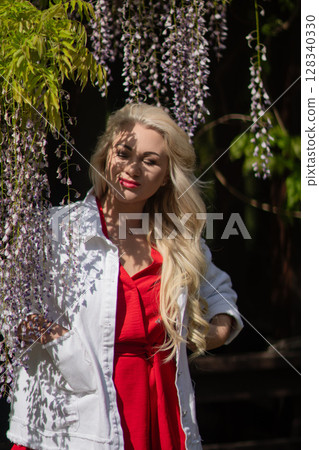 Wisteria Woman Portrait: Spring day, smiling lady poses in the garden during flowering season. 128340330