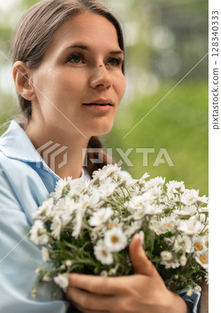 Woman Daisies Flowers: Girl holds bouquet outdoors, presumably in garden, enjoying fresh summer flowers now. 128340333