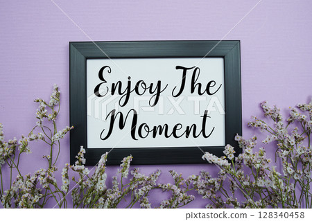 Enjoy The Moment text with flowers bouquet decoration on purple background 128340458