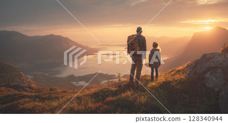 A father and son with backpacks stand atop a mountain, gazing at a breathtaking fjord landscape bathed in the warm, dramatic light of a sunset, symbolizing shared adventure and exploration 128340944