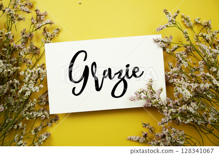 Grazie (Italian Language) text with flowers decoration on yellow background 128341067
