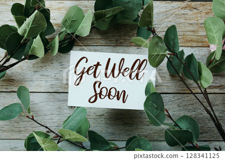 Get well soon text message with artificial green Eucalyptus leaf decoration on wooden background Get well soon text message with artificial green Eucalyptus leaf decoration on wooden background 128341125