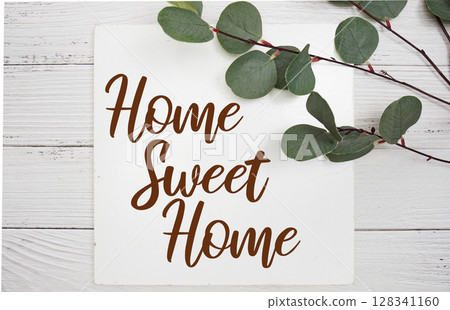 Home Sweet Home text with artificial green leaf eucalyptus on blue background Home Sweet Home text with artificial green leaf eucalyptus on blue background 128341160
