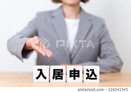 A middle-aged female business woman wearing a suit and a block of application for rent A middle-aged female business woman wearing a suit and a block of application for rent 128341343