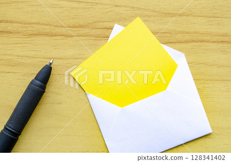 Yellow notepad in an envelope on wooden cover background. Customizable space for text 128341402
