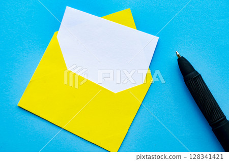 Top view of white notepad and pen with envelope on blue cover background with customizable space for text or ideas. 128341421