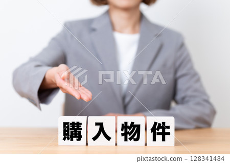 A middle-aged female business woman wearing a suit and a block of properties to purchase 128341484