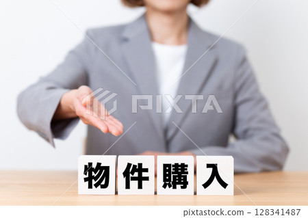 Middle-aged female business woman wearing a suit and a property purchase block 128341487