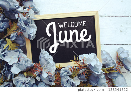Welcome June text with flowers frame decoration top view on wooden background, 128341822