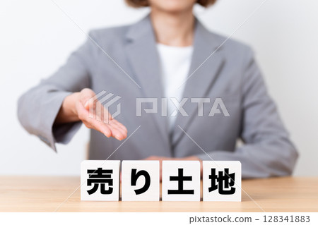 一位身穿西裝的中年女商人正在出售一塊土地 一位身穿西裝的中年女商人正在出售一塊土地 128341883