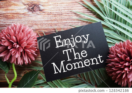 Enjoy The Moment Motivational and Inspirational quotes with flowers bouquet decoration on wooen background Enjoy The Moment Motivational and Inspirational quotes with flowers bouquet decoration on wooen background 128342186