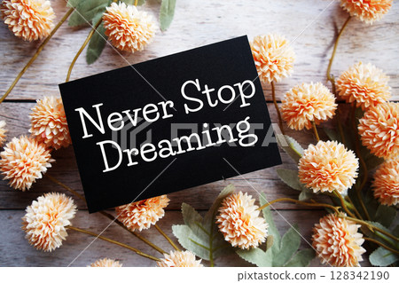 Never Stop Dreaming Motivational and Inspirational quotes with flowers bouquet decoration on wooen background 128342190