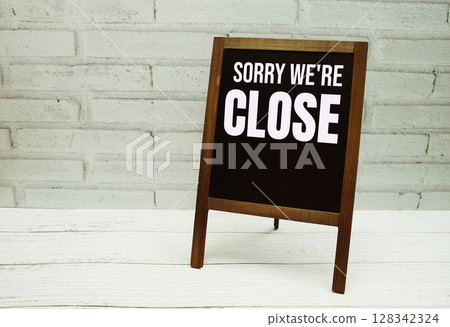 Sory we're Close sign with blackboard on white brick backgroun 128342324