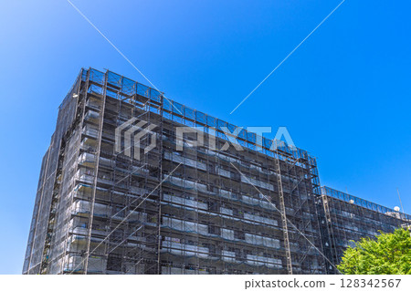 Yokohama cityscape in Japan: Apartment building repairs and inspections, scaffolding and protective nets. Satellite antenna outside the net = 9th 128342567