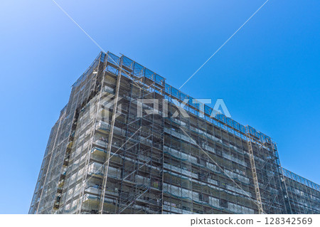 Yokohama cityscape in Japan: Apartment building repairs and inspections, scaffolding and protective nets. Satellite antenna outside the net = 9th 128342569