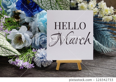 Hello March text write on paper card with wooden easel and flowers decoration on wooden background 128342733