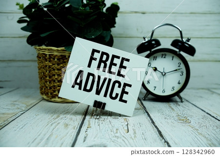 Free Advice text on paper card with alarm clock on wooden background 128342960