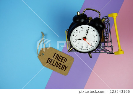 Free Delivery text on price tag with alarm clock and trolley shopping cart on pink, purple, blue geometric background 128343166