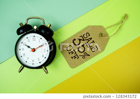 Sale 35% off text on price tag with alarm clock on green, yellow geometric background 128343172