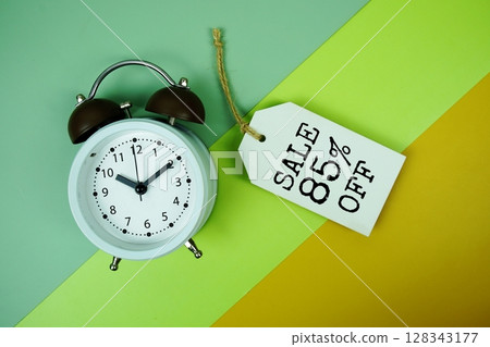 Sale 85% off text on price tag with alarm clock on green, yellow geometric background Sale 85% off text on price tag with alarm clock on green, yellow geometric background 128343177