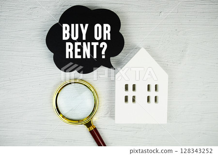 Buy or Rent? text message on speech bubble with house model and magnifying glass on concrete background 128343252