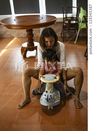 Mother And Toddler Riding A Toy Car In The House, Background for advertising and wallpaper in education and lifestyle scene. Mother And Toddler Riding A Toy Car In The House, Background for advertising and wallpaper in education and lifestyle scene. 128343387