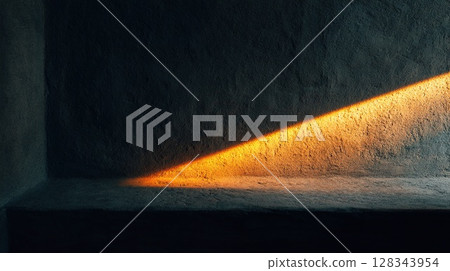 A diagonal beam of golden sunlight casts a stunning glow across a textured wall. 128343954