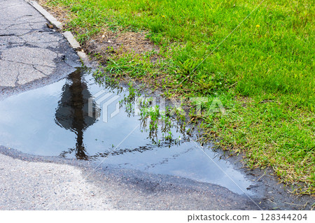 There is a small puddle of water located on the side of a road 128344204