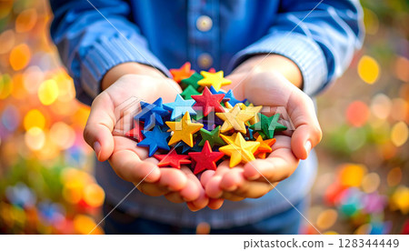 A child holding colorful stars in both hands A child holding colorful stars in both hands 128344449