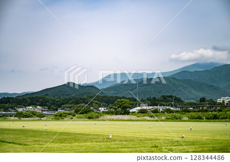 A soothing landscape photo of mountains, clouds, grass and birds in harmony 128344486