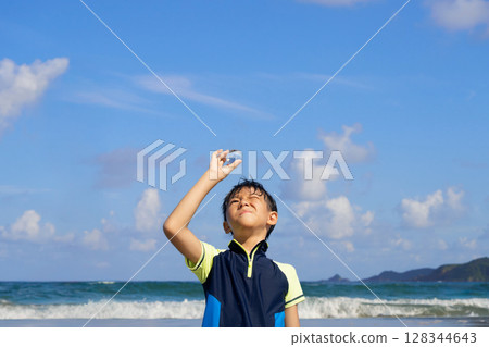 A boy staring at a transparent sphere on a summer beach A boy staring at a transparent sphere on a summer beach 128344643