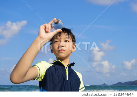 夏日海灘上,一個男孩盯著一個透明的球體 夏日海灘上,一個男孩盯著一個透明的球體 128344644