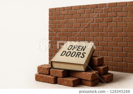 A book with the inscription OPEN DOORS lies in front of a brick wall. Space for text. A book with the inscription OPEN DOORS lies in front of a brick wall. Space for text. 128345289