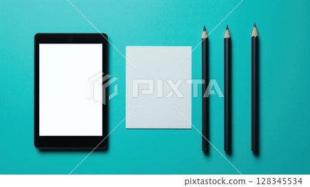 a flat lay of stationery items on a blue background. On the left side of the image, there is a black tablet with a blank white screen.	 128345534