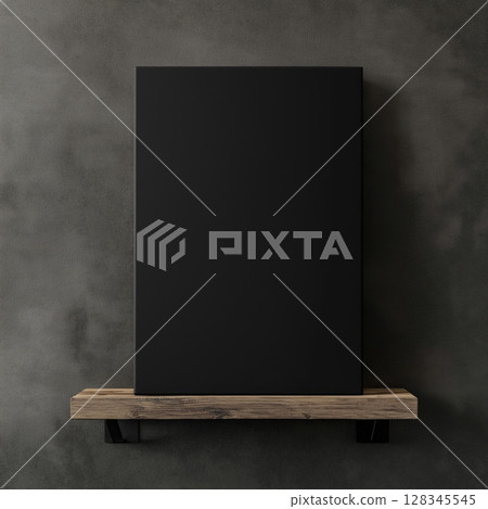 blank black canvas hanging on a wooden shelf against a gray concrete wall. The canvas is rectangular in shape and appears to be made of a light-colored wood	 128345545