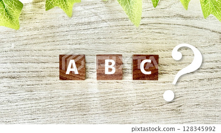 ABC letters and question marks on wooden cubes_whiteboard background ABC letters and question marks on wooden cubes_whiteboard background 128345992