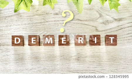白板背景上帶有 DEMERIT 字樣和問號的木製立方體 128345995