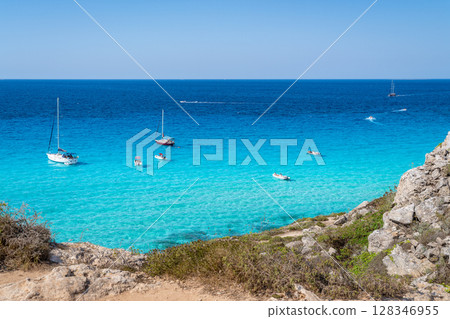 Boats and jet skis enjoy the turquoise waters off the rocky coast. Favignana, Cala Rossa 128346955