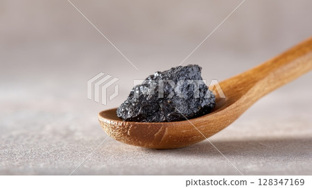 Shilajit herbal remedy in wooden spoon showcasing natural texture and health benefits 128347169