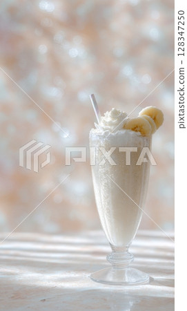 Creamy banana coffee shake topped with whipped cream and banana slices in a clear glass, showcasing a refreshing beverage 128347250