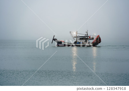 Brightly Lit Squid Fishing Boat Floating on Sea with Reflected Lights Brightly Lit Squid Fishing Boat Floating on Sea with Reflected Lights 128347918
