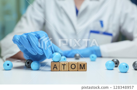 A scientist is meticulously examining atoms within a controlled laboratory environment 128348957