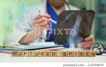 The doctor is carefully reviewing the Xray images to confirm a diagnosis of a ruptured spleen 128349644